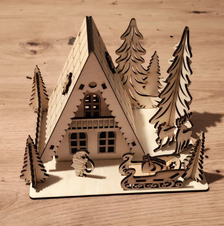 🎄 Un petit village de Noël qui s'illumine ✨
Chalet en bois découpé au laser, entouré de sapins, rennes et traîneau, avec une douce lumière chaleureuse.