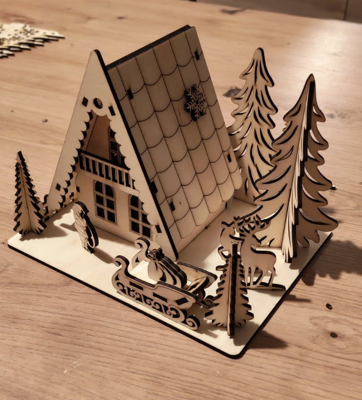 🎄 Un petit village de Noël qui s'illumine ✨
Chalet en bois découpé au laser, entouré de sapins, rennes et traîneau, avec une douce lumière chaleureuse.