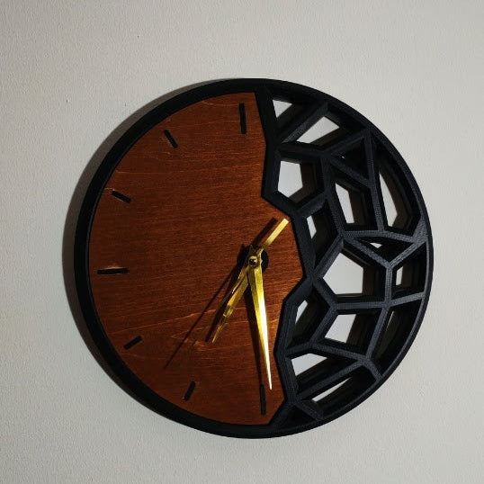 Horloge murale artisanale de 24 cm, associant bois naturel et impression 3D noire au design géométrique ajouré. Une création moderne et originale qui apporte une touche unique à votre décoration. 🕐