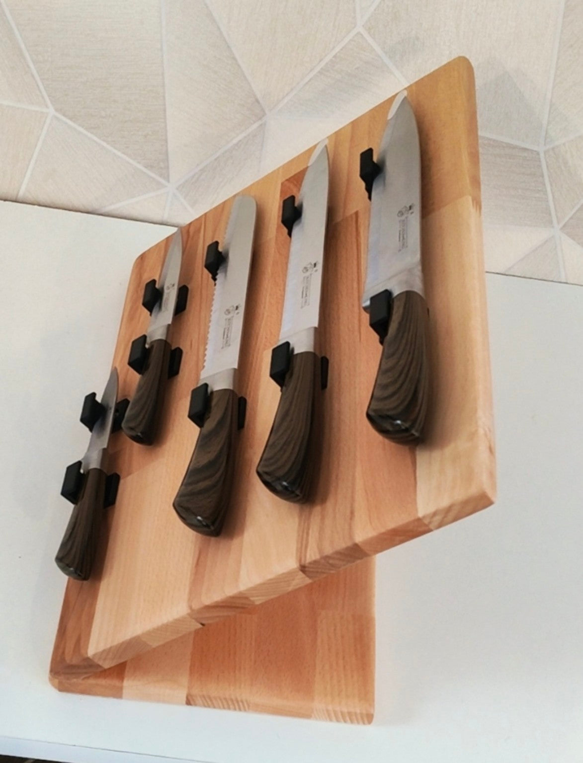 Présentoir incliné en bois pour 5 couteaux, équipé de supports individuels noirs pour maintenir et mettre en valeur chaque couteau tout en les gardant facilement accessibles.