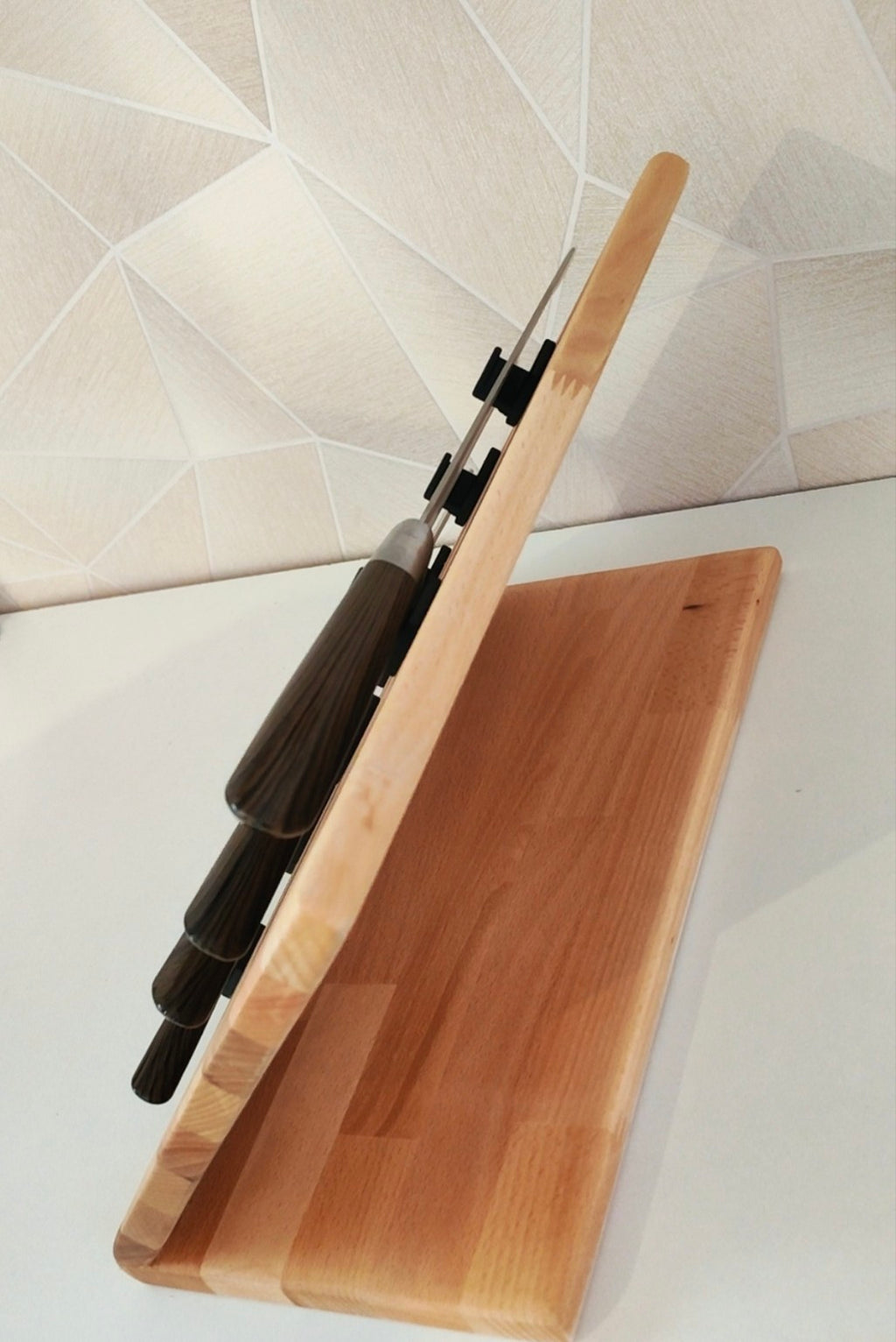 Présentoir incliné en bois pour 5 couteaux, équipé de supports individuels noirs pour maintenir et mettre en valeur chaque couteau tout en les gardant facilement accessibles.