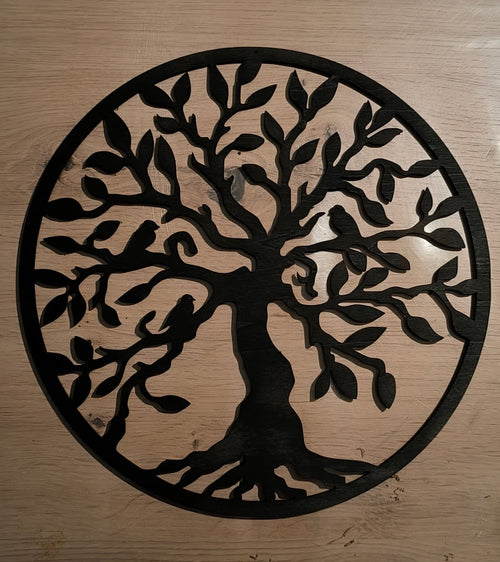 Arbre de vie mural en bois noir ajouré, avec branches et racines dans un cadre circulaire, sur un fond en bois