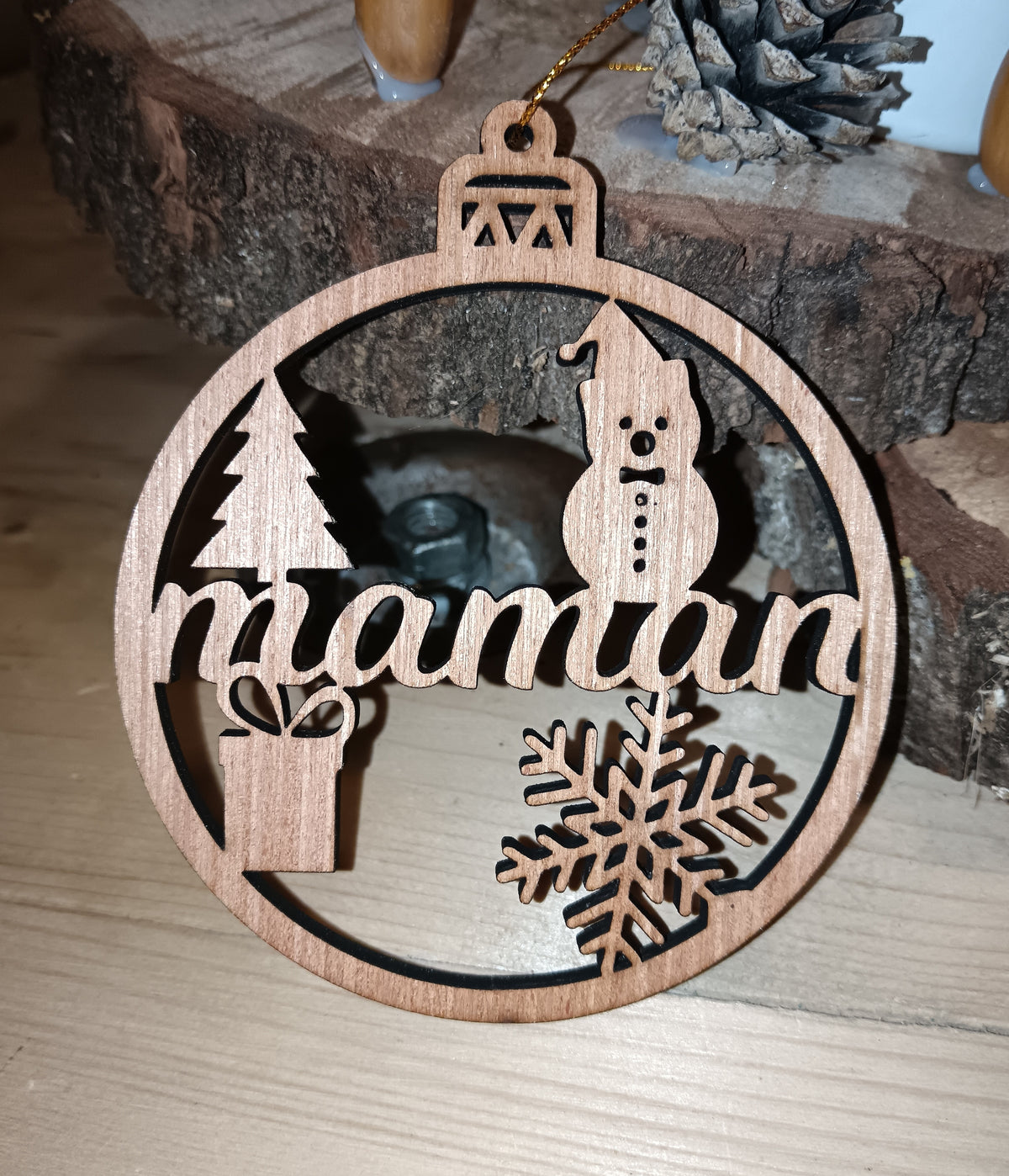 Boule de Noël personnalisée en bois gravée Maman, suspendue dans un sapin.