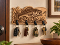 Porte-clés mural poisson en bois gravé avec quatre crochets noirs, présenté dans une entrée chaleureuse avec plusieurs trousseaux de clés suspendus.