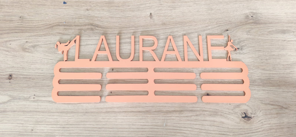 Support de médailles en bois rose personnalisé au prénom Laurane, avec silhouettes sportives