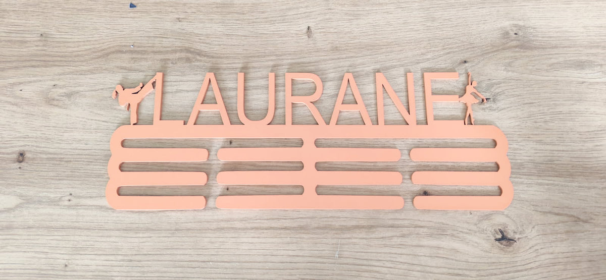 Support de médailles en bois rose personnalisé au prénom Laurane, avec silhouettes sportives